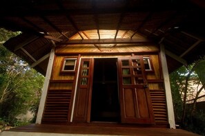 A wooden structure with a sloped roof and a doorway. - Les Acacias Bungalows Manambato (Brickaville)