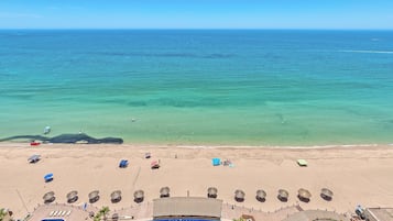 Un complexe hôtelier de bord de mer doté d’une piscine, de chaises longues, de parasols et offrant une vue sur l’océan.