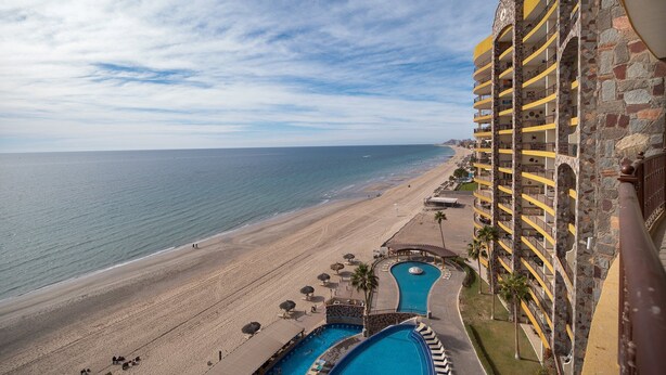 Un hotel frente a la playa con piscina y acceso directo a la orilla.