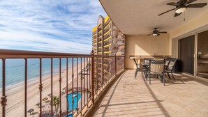 Un balcón con piscina, zona de comedor y vistas a la playa.