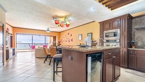 Una cocina amplia con una isla central, armarios de madera y un ventanal con vistas a un balcón.