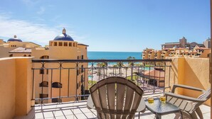 A balcony with a view of the sea, a pool area, and buildings with domed roofs. - Princesa Resort D-509 Whispering Sands Great Ocean View Condo (Puerto Peñasco)