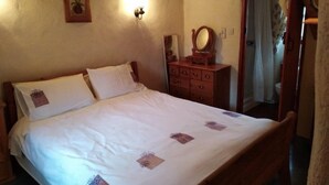 Une chambre à coucher avec un lit en bois, une commode avec un miroir et un luminaire fixé au mur.