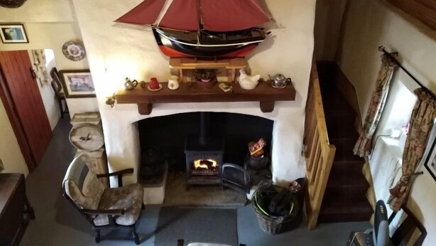Un salon chaleureux avec une cheminée, une cheminée en bois et un modèle de voilier décoratif.