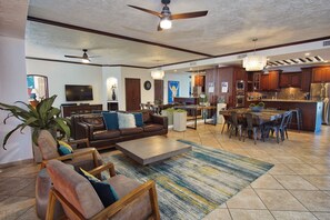 A spacious living area with a sofa, coffee table, and chairs, a dining area with a table and chairs, and a kitchen with modern appliances.