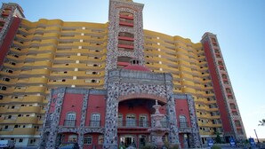 Un hotel de varios pisos con una fachada distintiva que presenta una torre central y una serie de balcones.