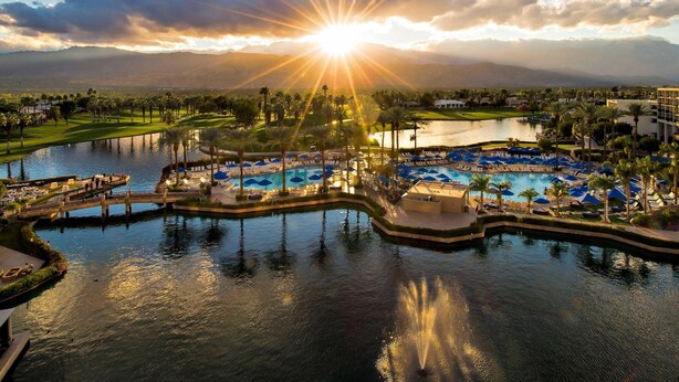 A resort with a pool area, palm trees, and a view of mountains.