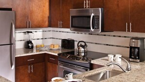 A modern kitchen with stainless steel appliances, granite countertops, and wooden cabinets.