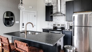 Una cocina moderna con una isla central, electrodomésticos de acero inoxidable y armarios negros.