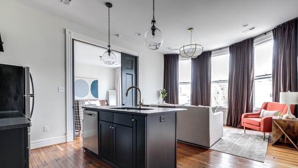 Una cocina moderna con armarios oscuros, una isla central e iluminación colgante.