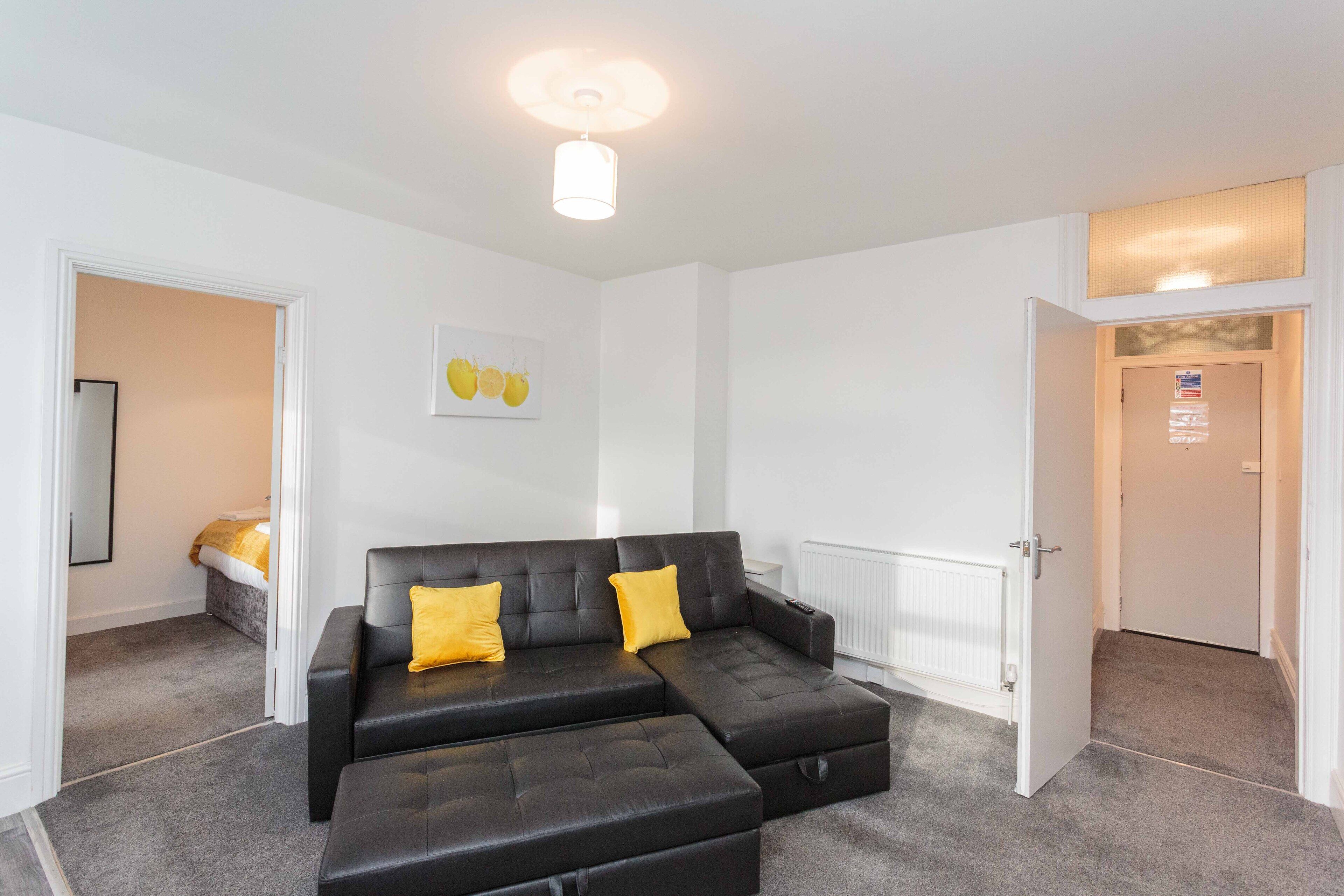 A modern living room with a sectional sofa, a small table, and a door leading to another room.
