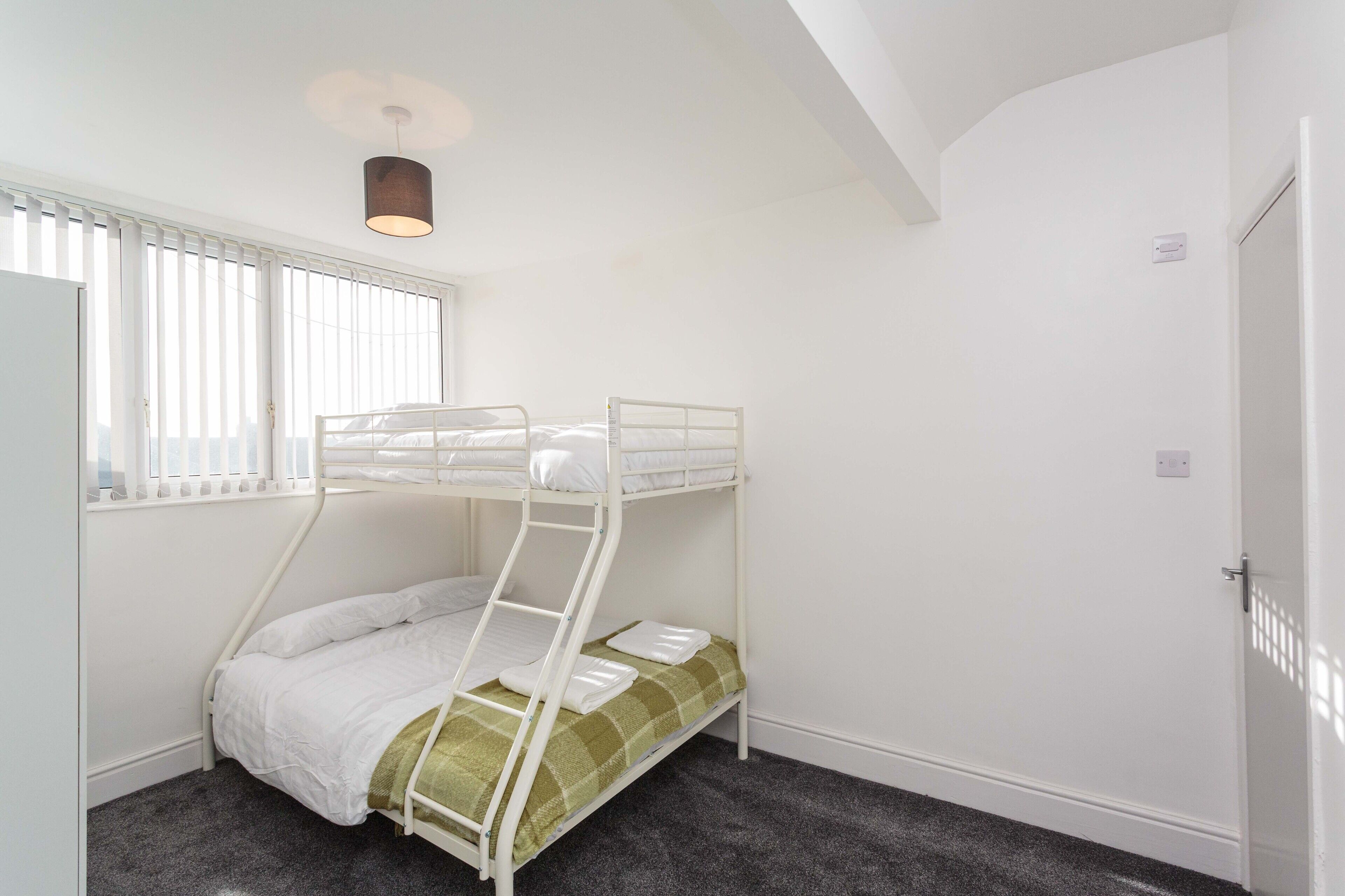 A bunk bed room with a window, a door, and a ceiling light.