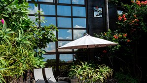 A patio area with a glass wall, outdoor seating, and various plants. - Caloura 66 - Vacation Villa (Lagoa)