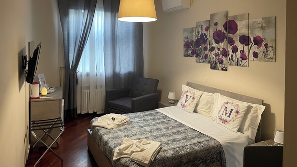 Une chambre à coucher avec un lit, une chaise, un bureau et un tableau accroché au mur.