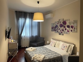 Un dormitorio con cama, una silla, un escritorio y un cuadro en la pared.