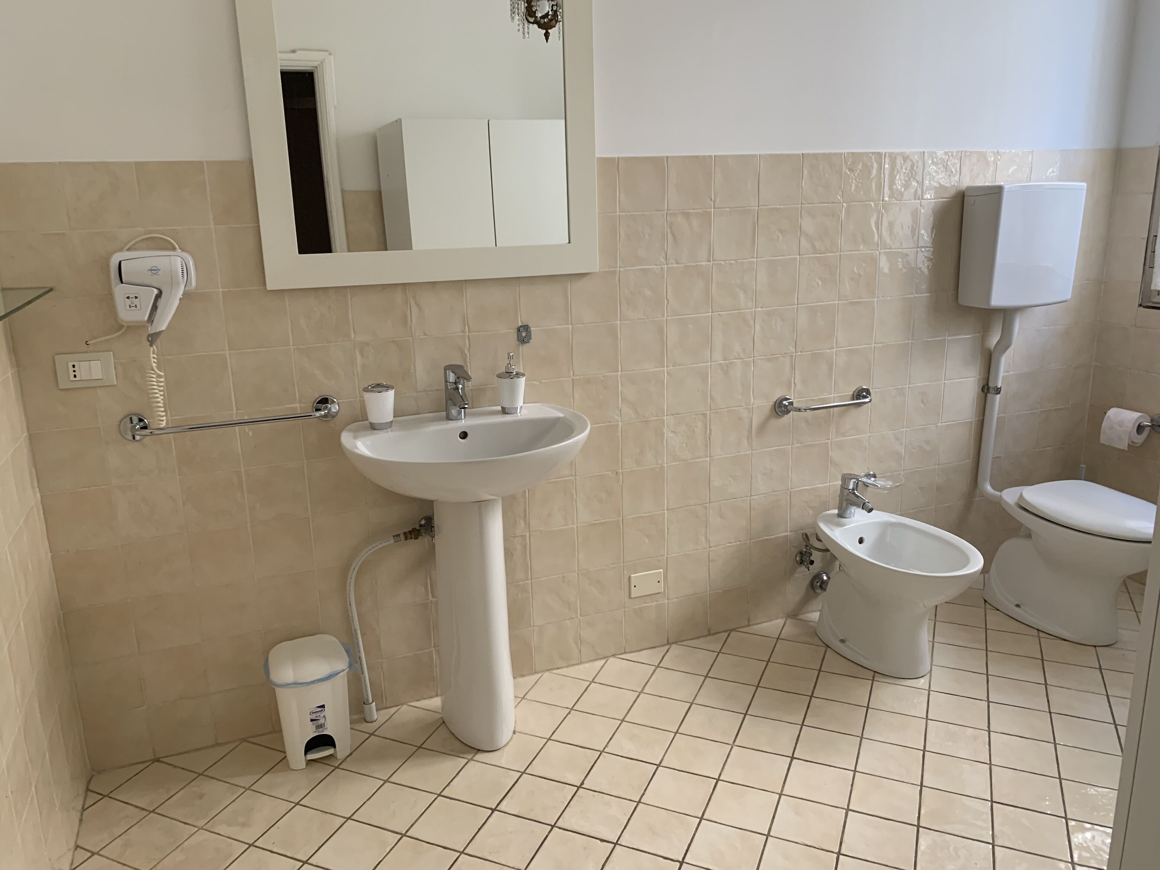 Un baño con lavamanos, inodoro, bidé y espejo.
