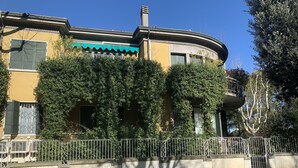 Un bâtiment à la façade incurvée, doté de volets verts et d’un balcon.