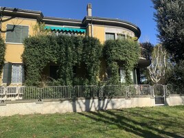 Un edificio con fachada curva, contraventanas verdes y un balcón.