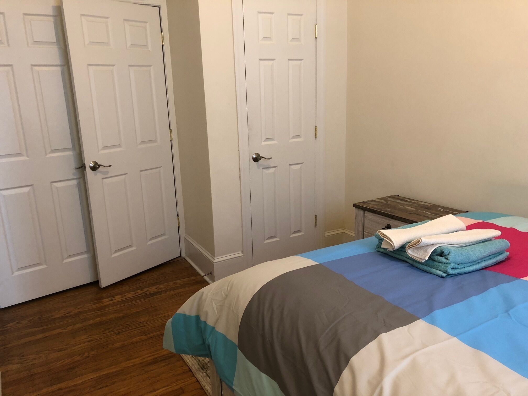 A bedroom with a bed, a small nightstand, and two white doors.
