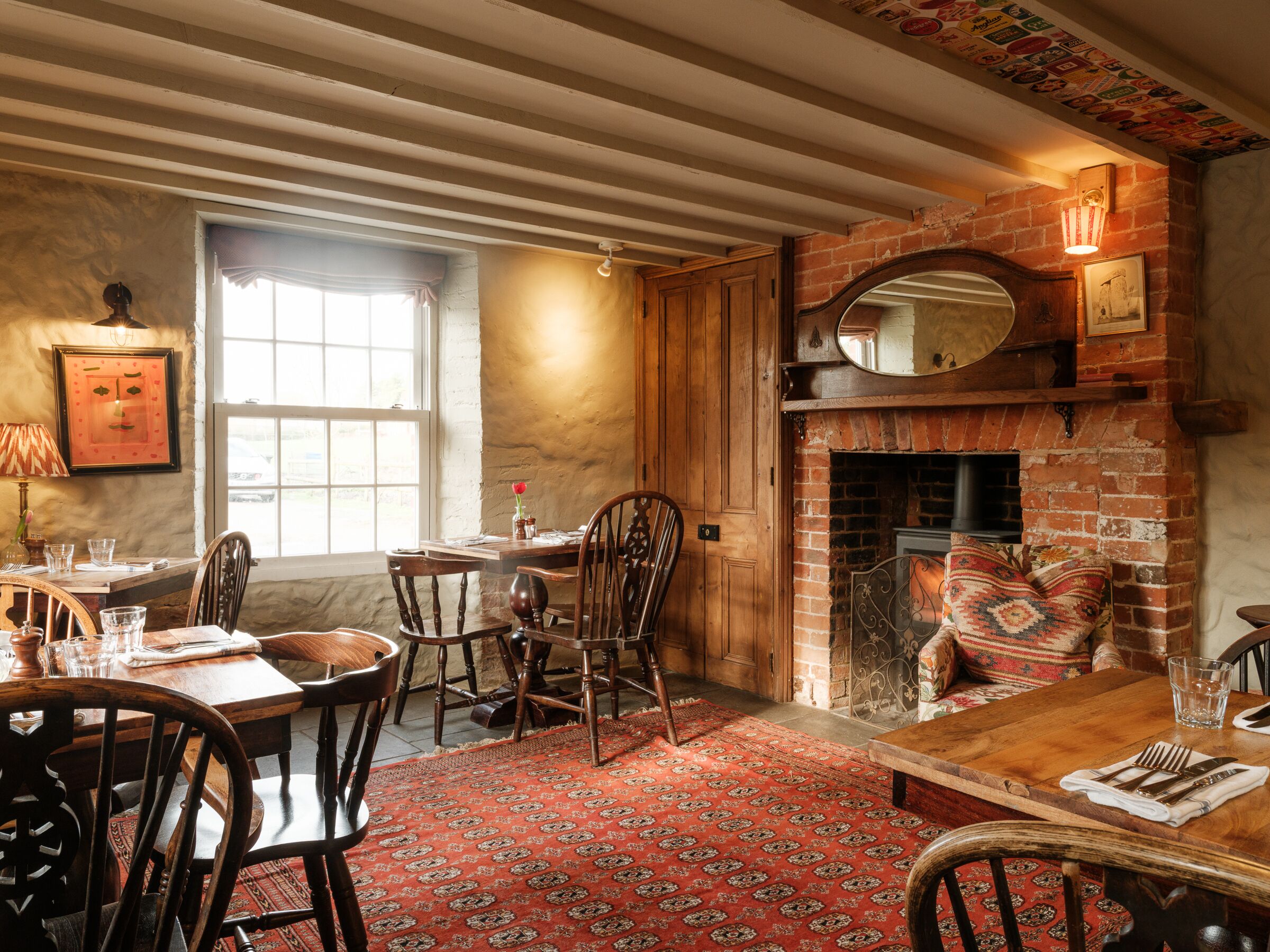 A traditional dining room with a brick fireplace, wooden furniture, and a patterned rug.