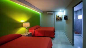 A hotel room with two beds, a nightstand with a lamp, a wall-mounted air conditioner, and a door leading to a bathroom. - HC Express (Monterrey)