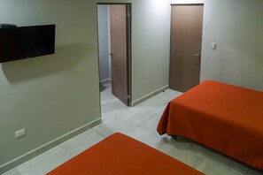 Quarto de hotel com duas camas, uma TV de tela plana na parede e uma porta para o banheiro.