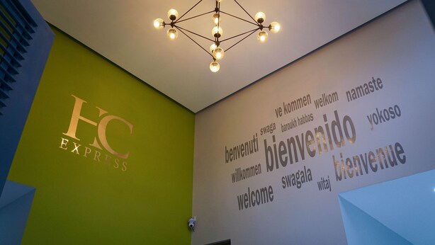A hotel reception area with a green wall and a sign reading "HC EXPRESS". - HC Express (Monterrey)