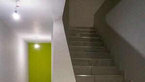 A staircase with a handrail, a green wall, and a door at the bottom. - HC Express (Monterrey)