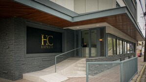 A hotel entrance with a stone facade, a metal railing, and a staircase leading to the entrance. - HC Express (Monterrey)