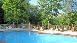 A swimming pool with lounge chairs and a wooden deck. - Believe, 2 Bedrooms, Pool Access, Wifi, Hot Tub, Pet Friendly, Sleeps 6 (Gatlinburg)
