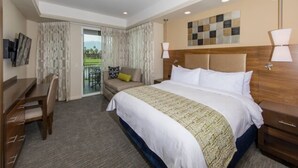 A hotel room with a large bed, a desk, a chair, and a view of the outdoors.
