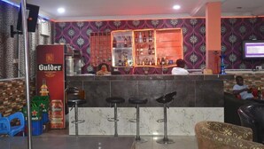 A bar area with a counter, stools, and shelves of bottles. - Evaville Hotel N Lounge (Port Harcourt)