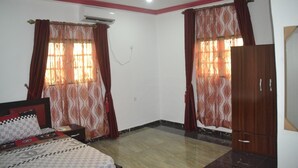 A bedroom with a bed, a wardrobe, and two windows with curtains. - Evaville Hotel N Lounge (Port Harcourt)