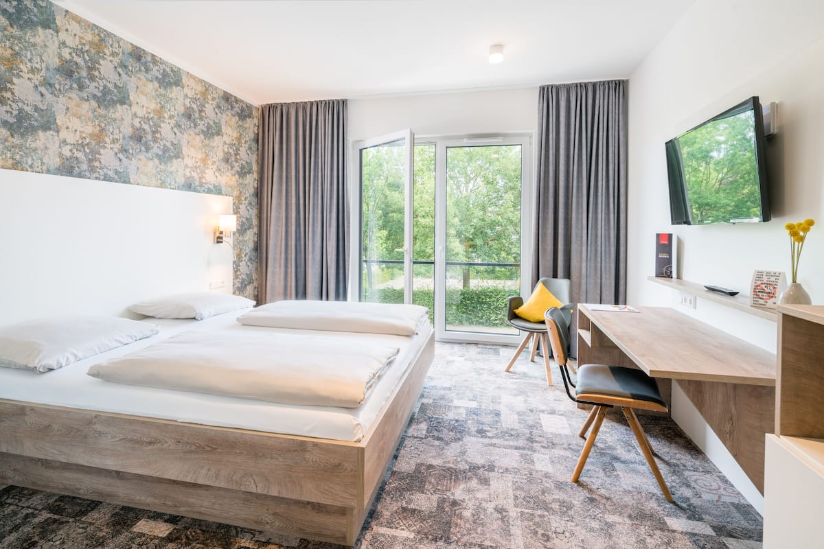 A modern hotel room with a large bed, a desk, and a TV.