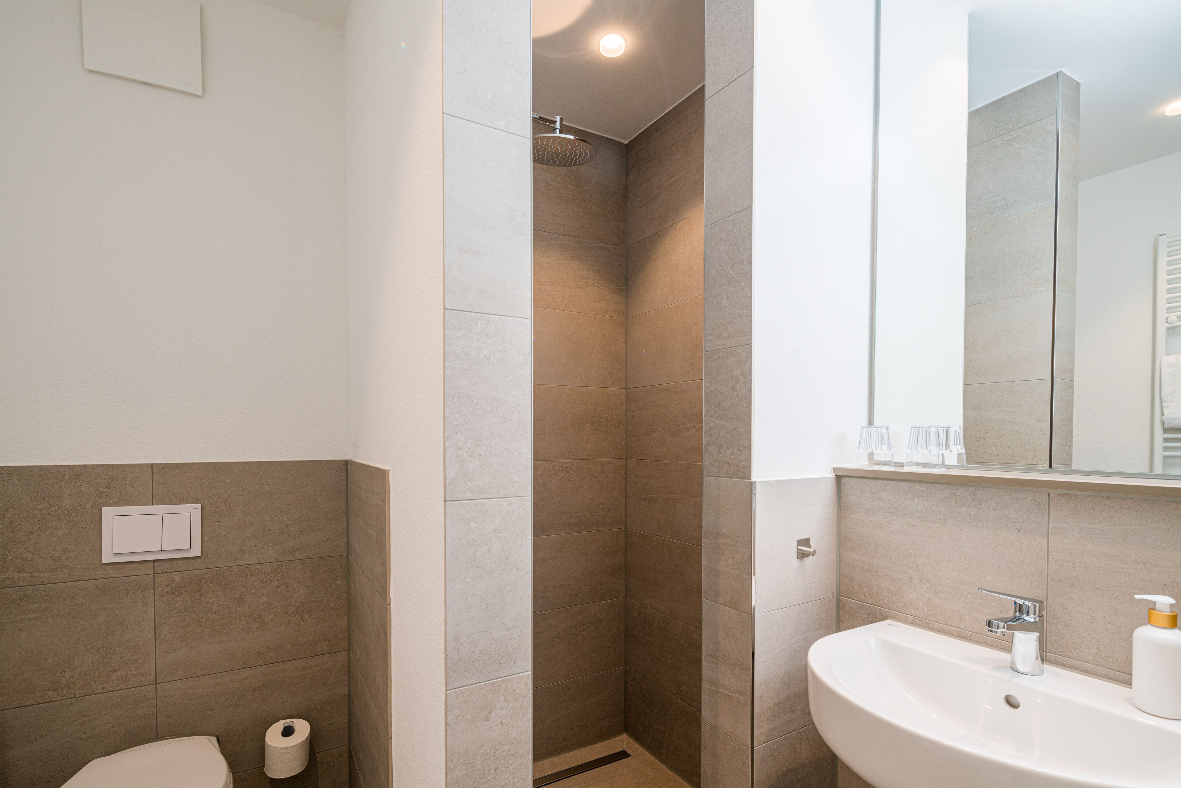 A modern bathroom with a shower, toilet, and sink.