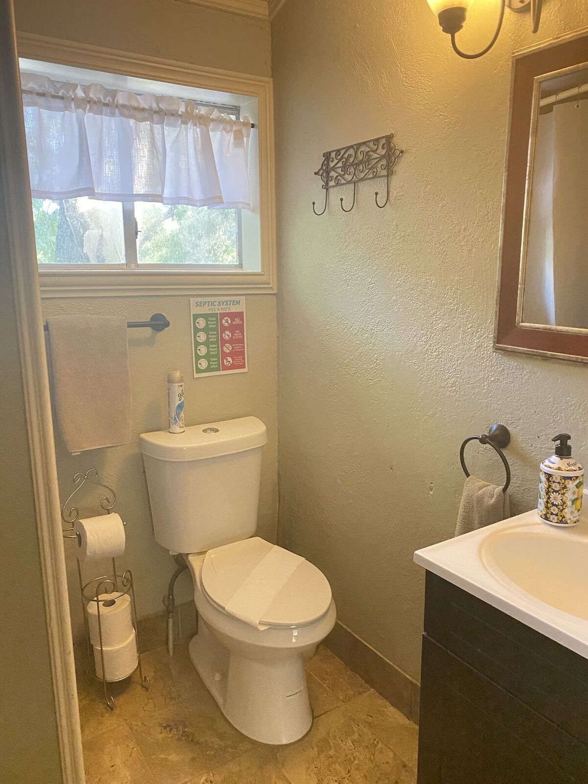 A small bathroom with a toilet, sink, and window.