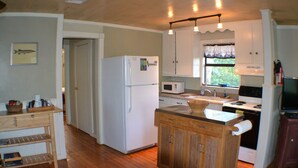 A compact kitchen with a refrigerator, microwave, sink, and wooden cabinets. - Lago Haus, Top Unit, Rustic Wundercove Cottage, Access to Shared Pool and River (New Braunfels)