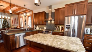 A modern kitchen with wooden cabinets, stainless steel appliances, and a granite countertop. - Amazing Upgraded Chalet with Everything You Need and It's ALL Yours - No Suite (Silver Star Mountain)