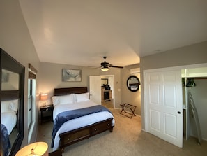 Cozy retreat with a large bed, ceiling fan, and wall-mounted mirror.