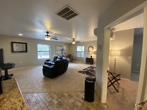 Relax in this spacious living area with a high ceiling, featuring a large leather sofa, dining table, and side table.