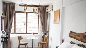 A bedroom with a large bed, a small table, two chairs, and a window with curtains. - Pandan Karakoy Suit (Istanbul)