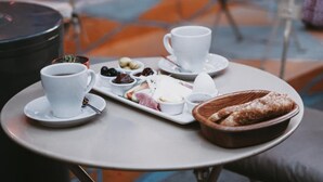 A café table with a tray of pastries, a cup of coffee, and a plate of food. - Pandan Karakoy Suit (Istanbul)