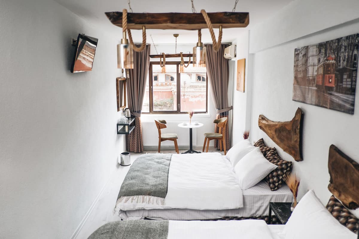 A bedroom with a bed, a small table, chairs, and a window with curtains.