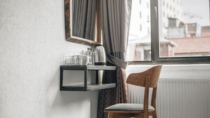 A room with a wooden chair, a shelf with kitchen items, a window with curtains, and a view of buildings outside. - Pandan Karakoy Suit (Istanbul)