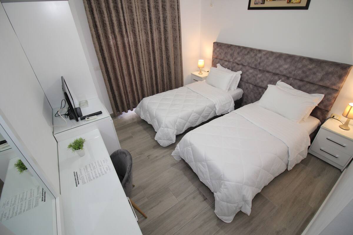 Une chambre d’hôtel avec deux lits, un bureau, une chaise et un téléviseur.