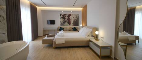 Una habitación de hotel moderna con una cama grande, un área de descanso, una bañera y un espejo amplio.