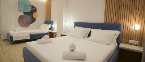 Habitación de hotel con una cama grande, una cama más pequeña, una obra de arte en la pared y un panel de madera.