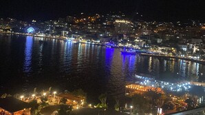 A nighttime cityscape with a waterfront, illuminated buildings, and a Ferris wheel. - Julia Hotel (Sarandë)