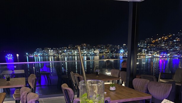 A restaurant with outdoor seating overlooking a cityscape at night. - Julia Hotel (Sarandë)