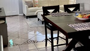 A dining area with a table, chairs, and a white sofa in the background. - North Lakeland bungalow (Lakeland)
